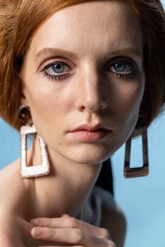 Close-up portrait of a woman with striking earrings and makeup, showcasing modern beauty.