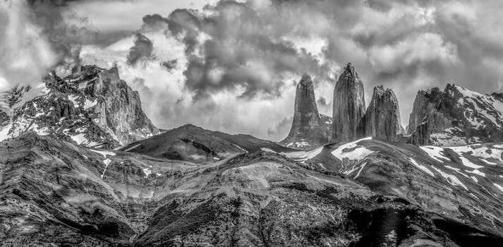 Monochrome view of Torres del Paine peaks under a dramatic cloudy sky.