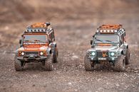 Small toy figures of off road cars with shining headlights placed on ground