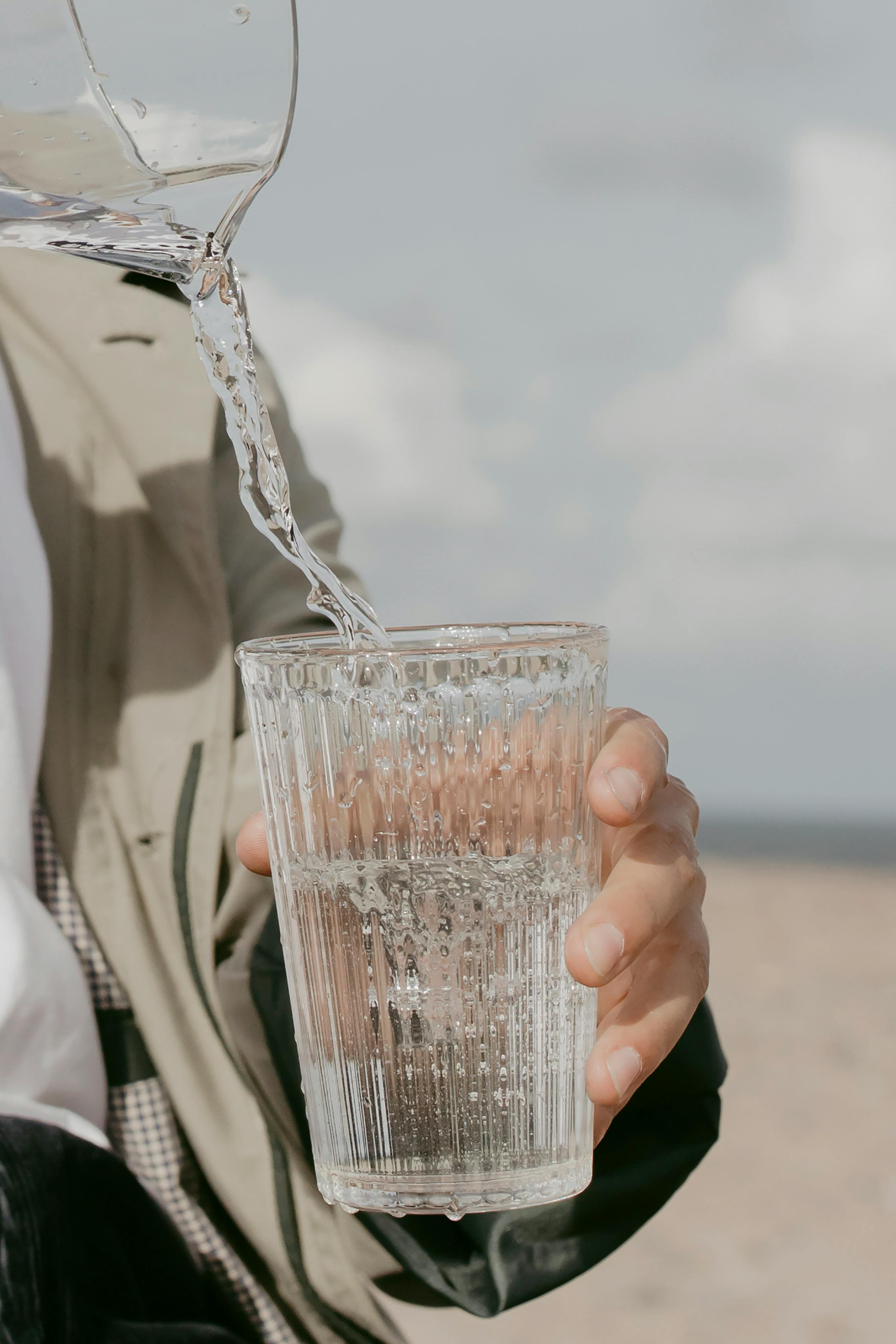 水被倒入户外海滩手持玻璃杯的特写镜头