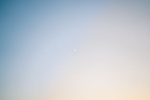 Soft gradient sky at twilight featuring a small crescent moon.