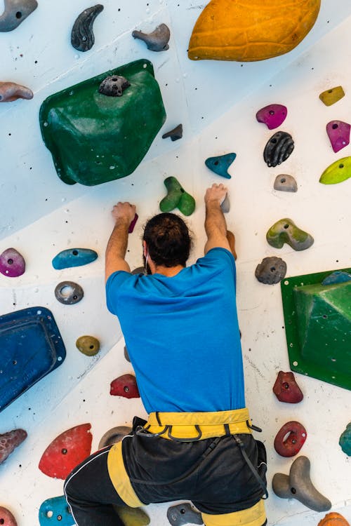 Strong climber ascending artificial boulder wall