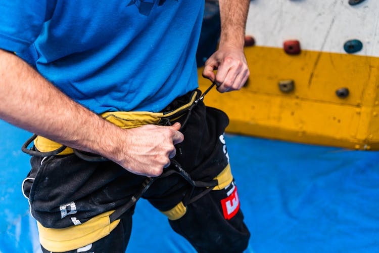 Male Climber Fastening Safety Harness Before Ascending