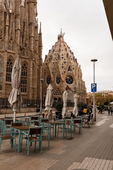 View of the majestic Sagrada Familia with adjacent seating area and iconic Gothic elements in Barcelona.