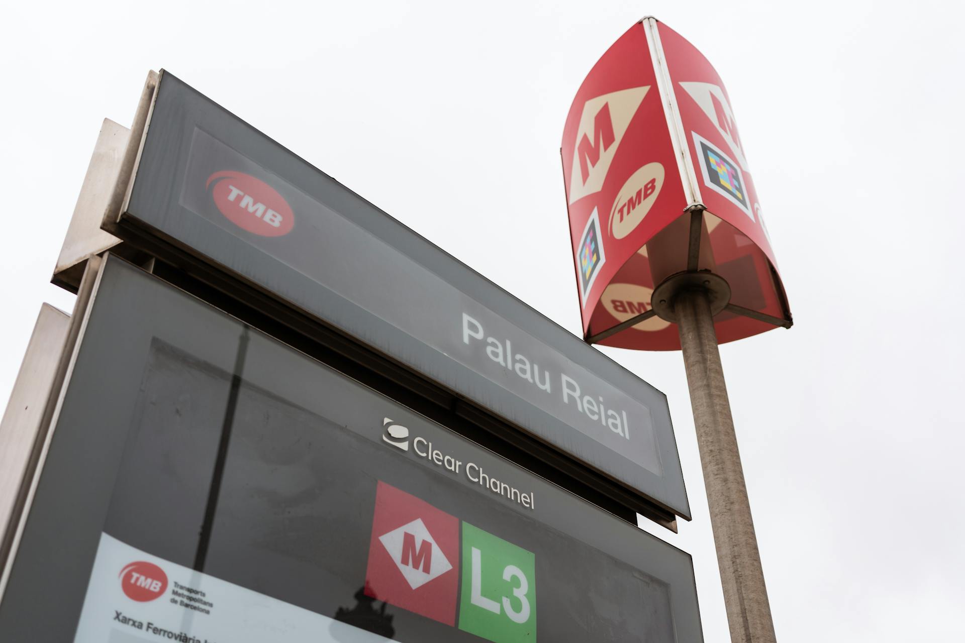 Palau Reial metro sign with TMB and Clear Channel logos in a city environment.