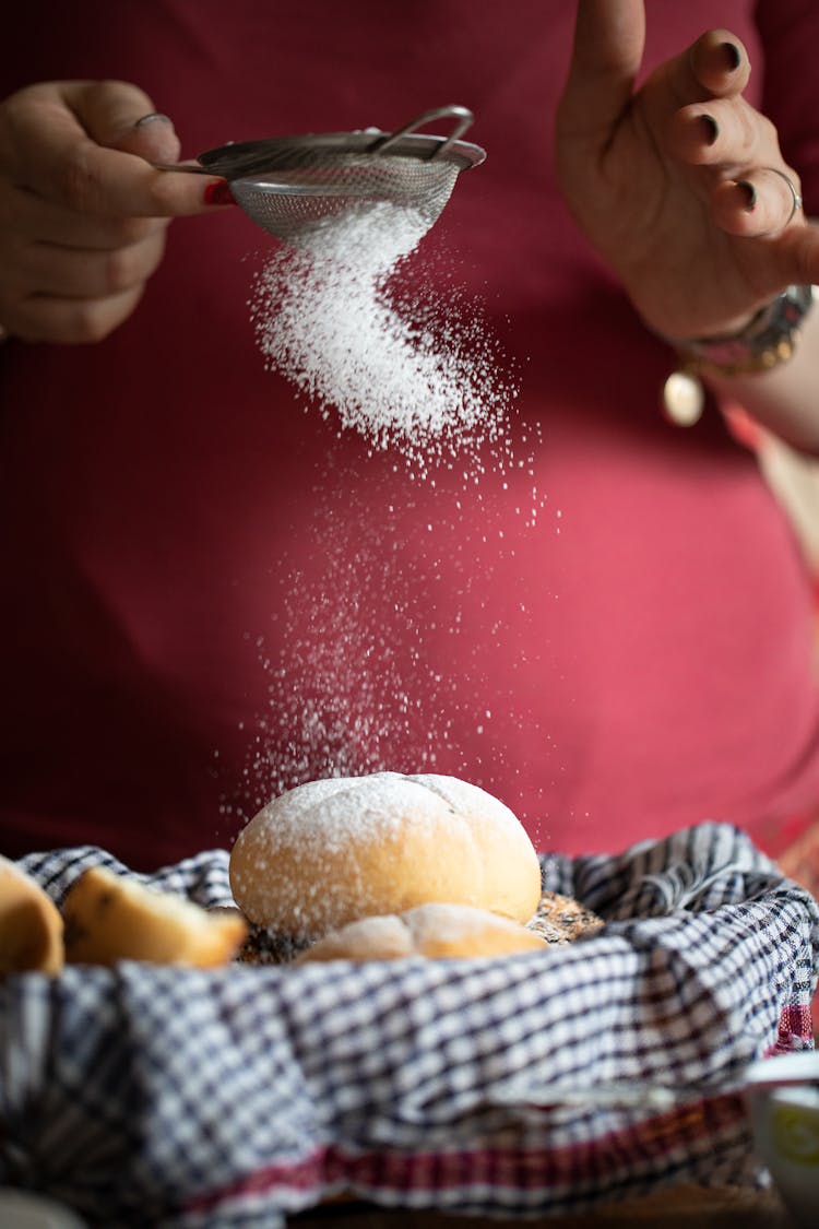 A Woman Sifting Icing Sugar On A Bread