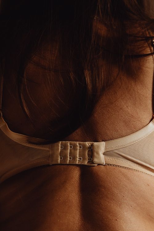 Free Close-up of a woman's back showing bra straps and skin texture in warm lighting. Stock Photo