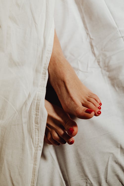 Free Feet with Red Pedicure on White Sheets Stock Photo