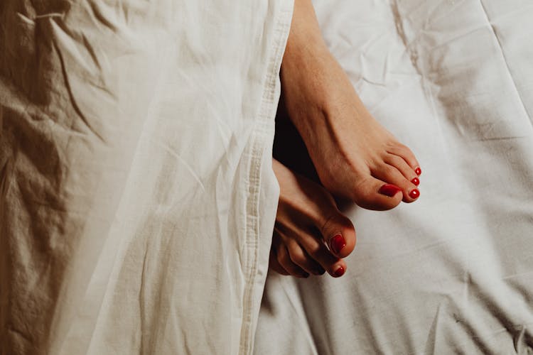 Female Feet Sticking From Under A Duvet 