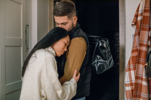丈夫轻轻拥抱背对着他的妻子，表情温和