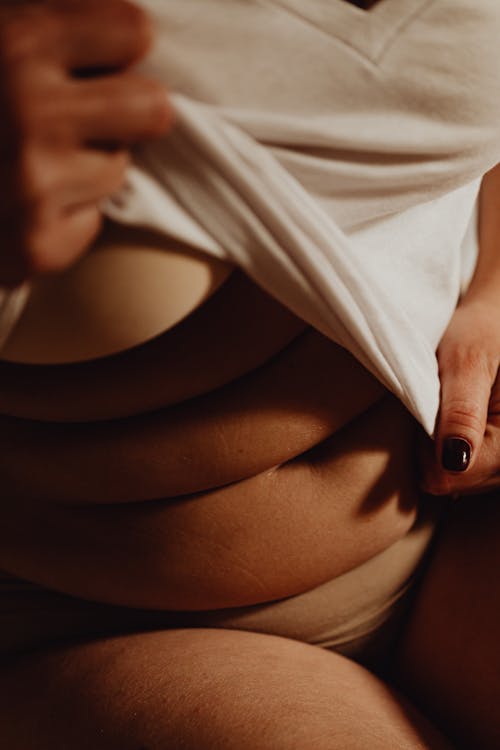 Free A Woman in White Shirt and Beige Bra Showing Her Belly Stock Photo