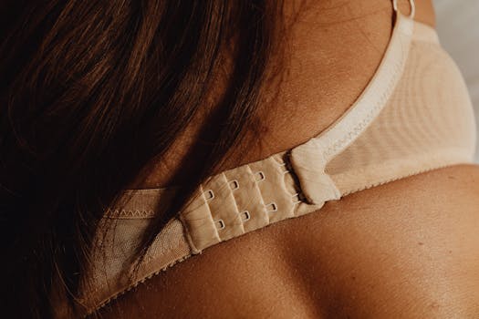 Intimate close-up of a beige bra clasp on skin, highlighting details and texture.