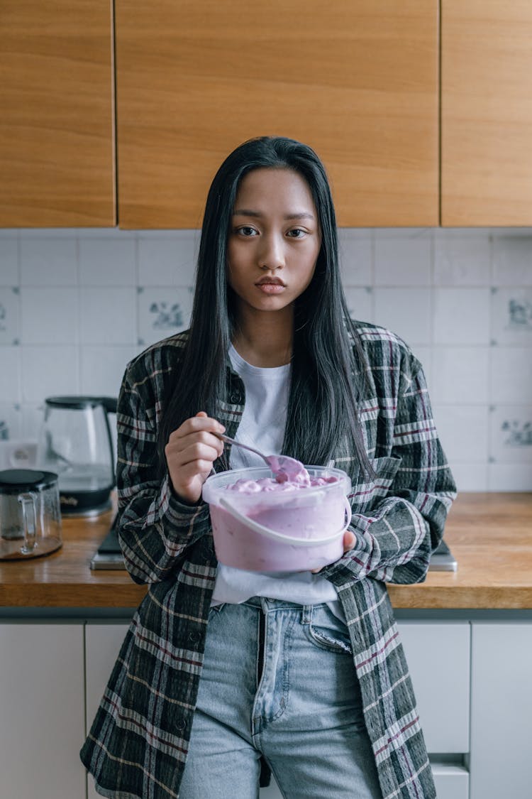 A Sad Woman By The Kitchen Counter Holding A Pail Of Ice Cream