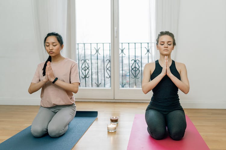 Two Women Kneeling On Yoga Mats