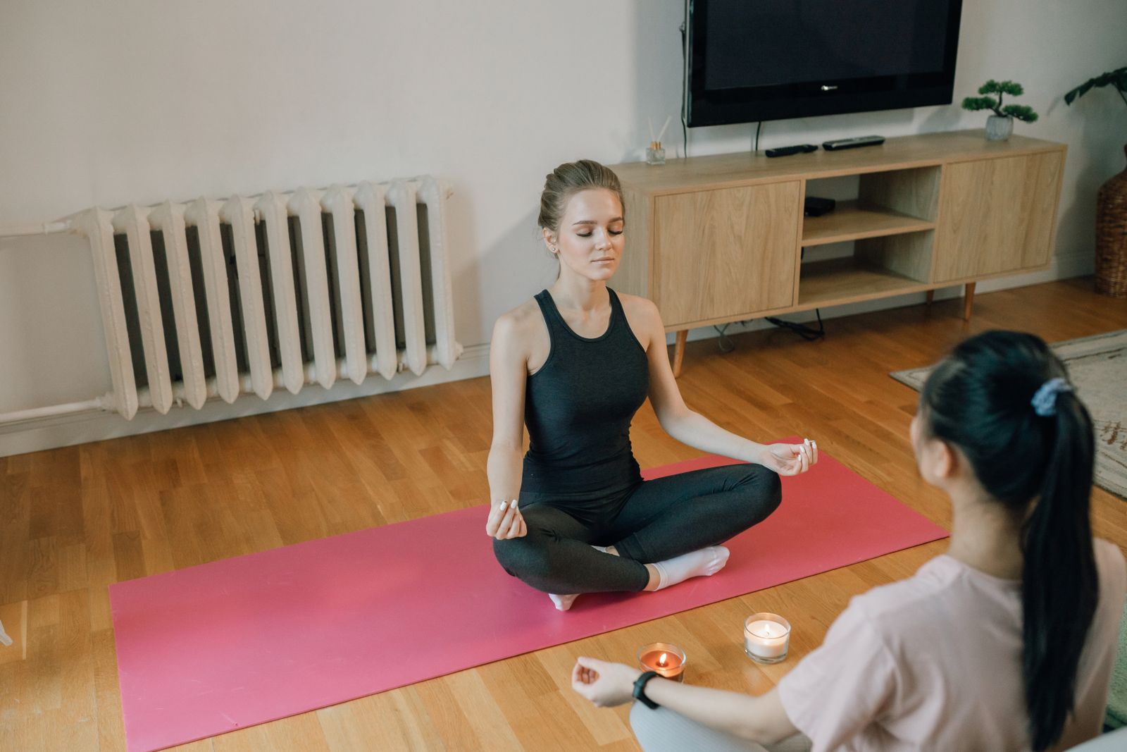 Beginner sitting cross-legged on a mat practicing meditation for beginners at home