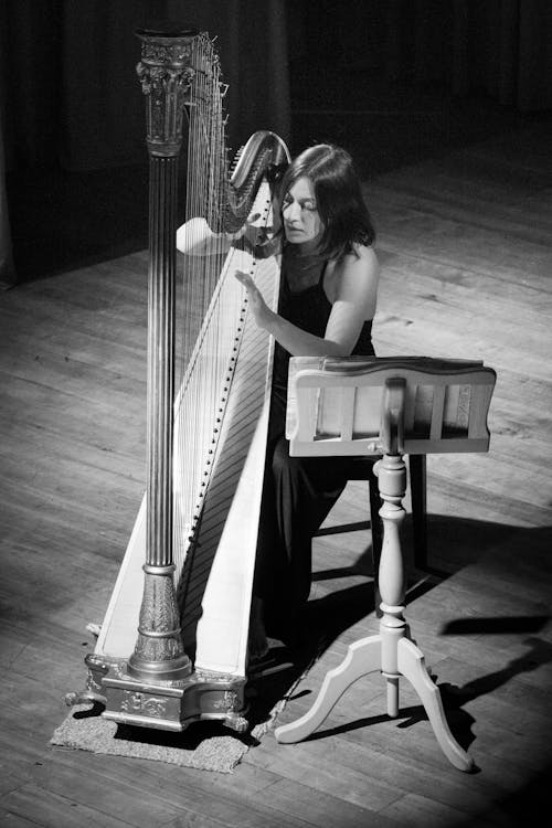 Grayscale Photo of a Woman Playing a Harp