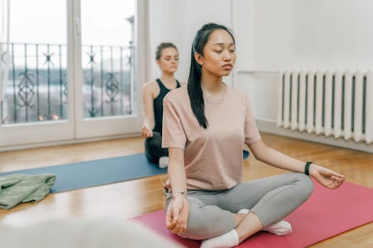 Two women practicing yoga in a serene indoor setting, focusing on meditation and mindfulness.
