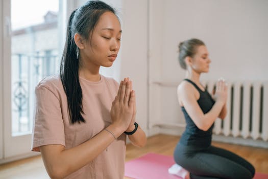 Two women engaging in a serene yoga practice, focusing on meditation for mental wellness.