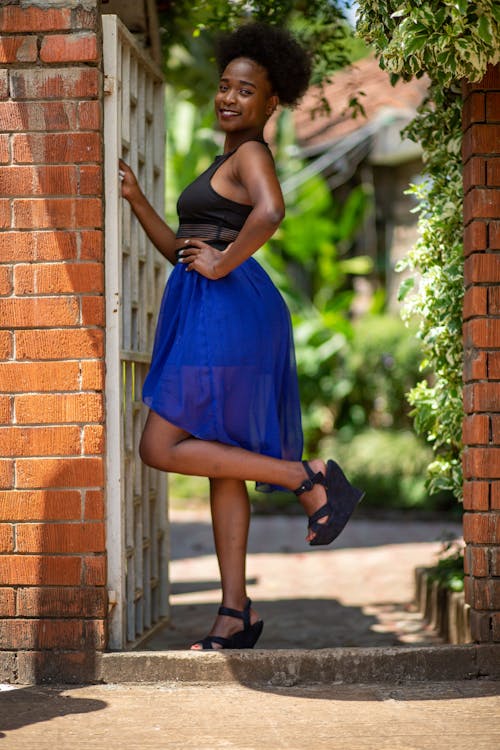 Woman in Black and Blue Dress Standing Near Brick Wall
