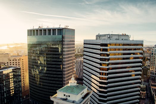 Aerial view of modern office buildings with sunrise reflections in a vibrant urban skyline.