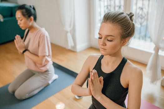 Two women practicing yoga meditation indoors, focused on relaxation and mindfulness.