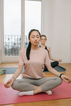 Two women practicing yoga meditation indoors for relaxation and mental health.