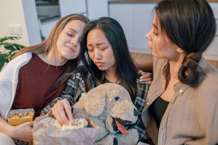 Women Sitting With Eyes Closed And Eating Popcorn