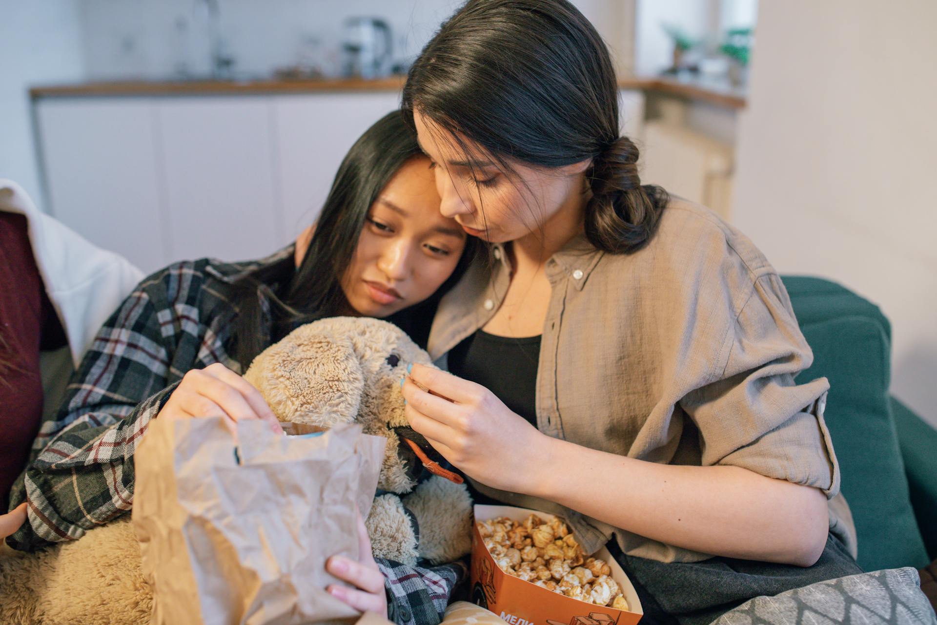 A Woman with a Stuffed Toy Getting Comforted by Her Friend