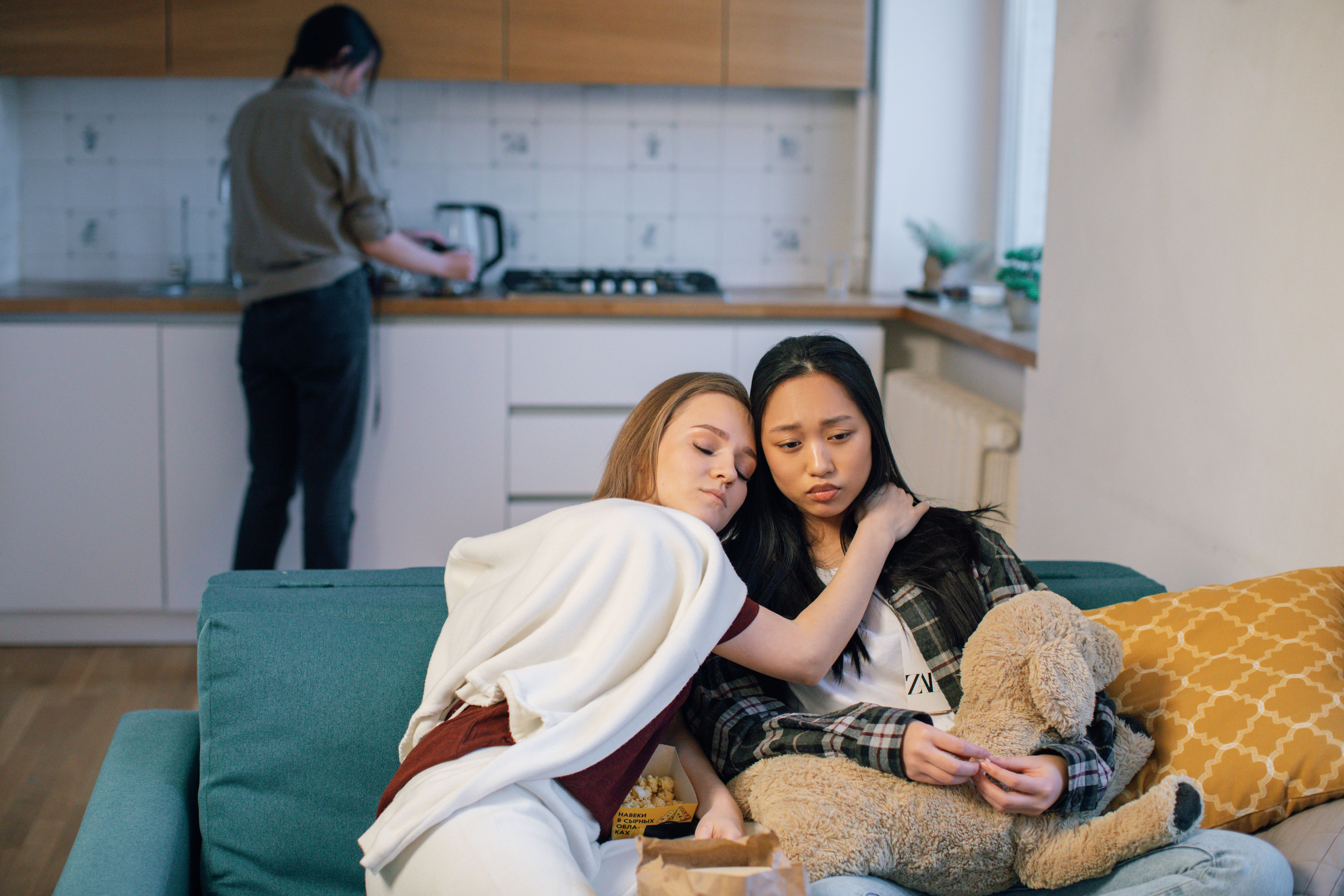 Two women on a couch offering emotional support, indoors.