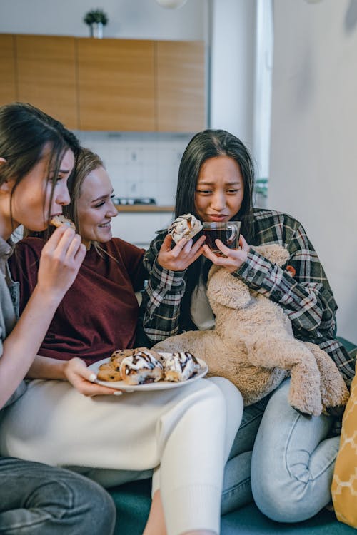 Free A Woman Eating a Cookie while Getting Comforted by Her Friend Stock Photo