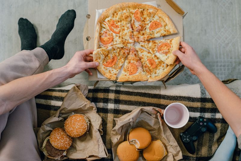 Hands reaching for a slice of pizza from an open box