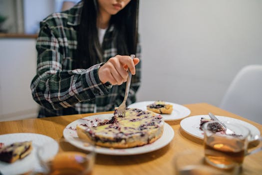 A person cuts a slice of homemade berry pie at a dining table, creating a cozy and inviting atmosphere.