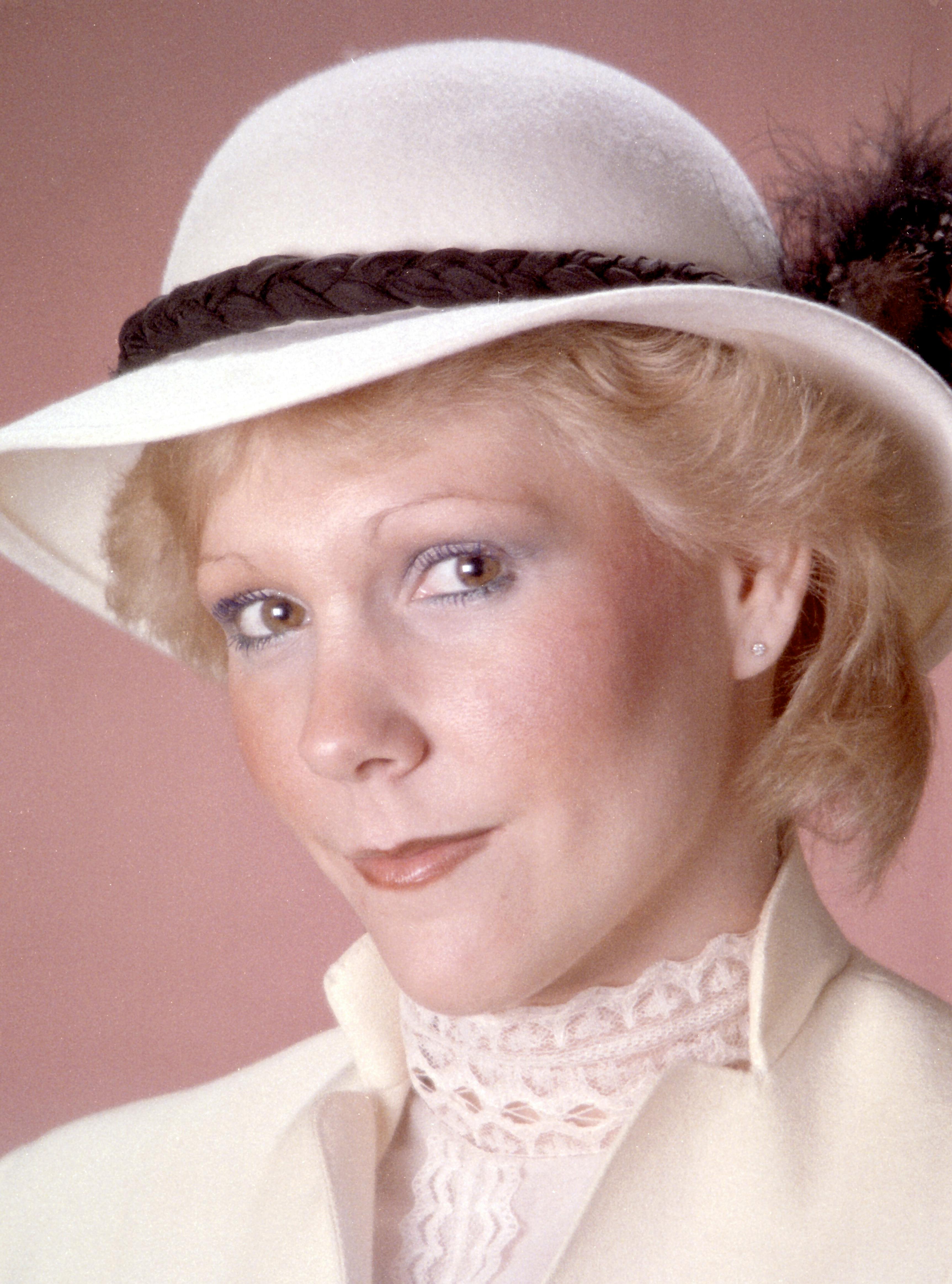 Close-up portrait of a stylish woman wearing a vintage hat and lace blouse with a soft background.