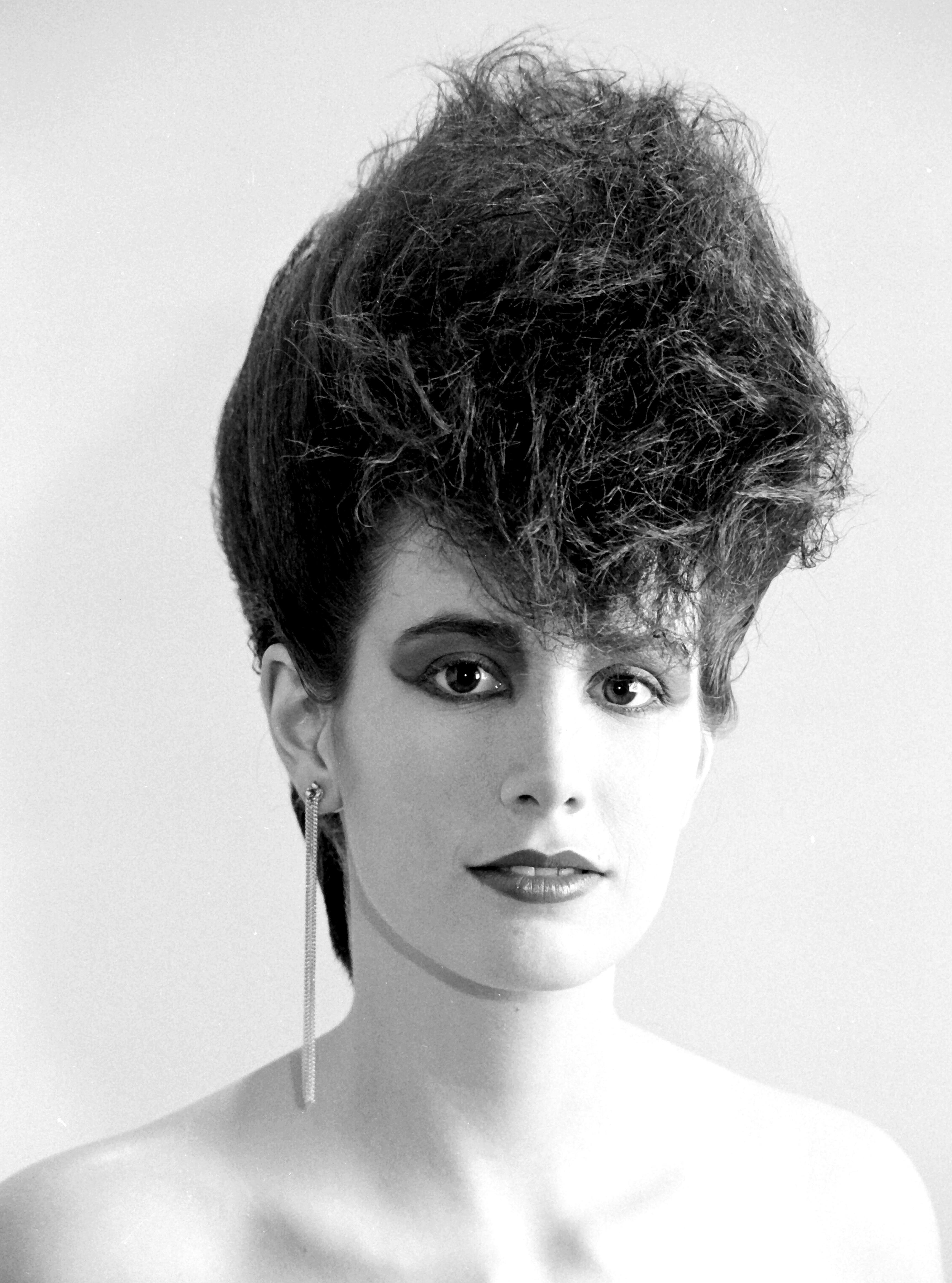 Stylish black and white portrait of a woman with an 80s hairstyle, showcasing vintage fashion.