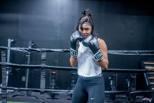 Free Confident young woman in boxing gloves posing in a gym ring. Stock Photo