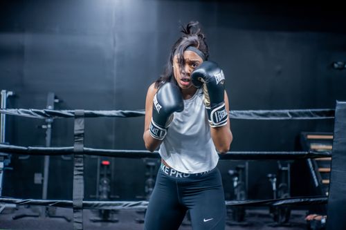 Free Athletic woman in a boxing ring wearing gloves, showing determination and strength. Stock Photo
