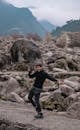 A Man in Black Long Sleeves Standing on a Rocky Field