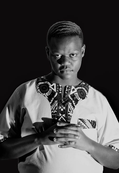 Black man in ethnic shirt looking at camera against black background