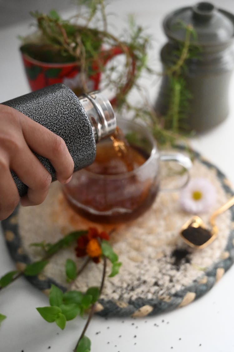 A Hand Pouring Tea From The Stainless Tumbler