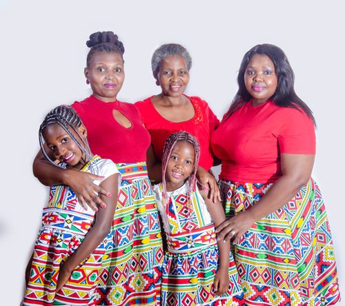 Free Cheerful ethnic women embracing cute little girls with Afro braids in bright national dresses on white background Stock Photo