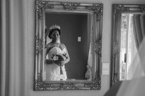 Free Black and white of young African American female in diadem and white dress with delicate flowers looking at mirror Stock Photo