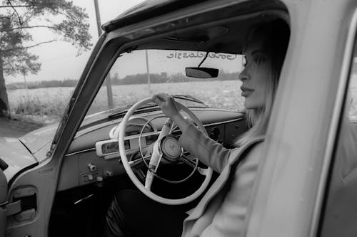 Free Black and white of thoughtful woman driving retro car in countryside and looking away in daytime Stock Photo