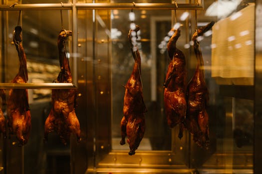 Hanging roasted ducks in a warm-lit display case, showcasing Asian street food tradition.