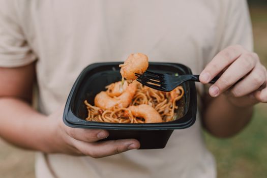 Tasty Asian noodles with shrimp being held in hands, ideal for food enthusiasts.