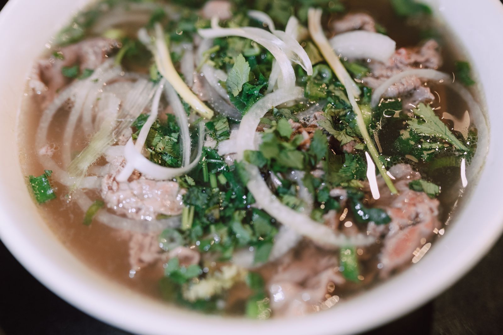 Top-down bowl of beef pho with sliced beef, cilantro and onion