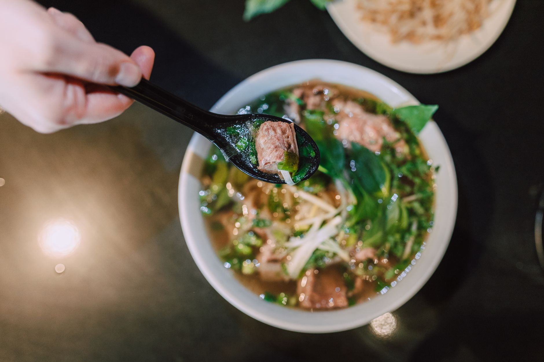 Top view of a delicious bowl of Vietnamese pho with beef and fresh herbs, showcasing traditional Asian cuisine.