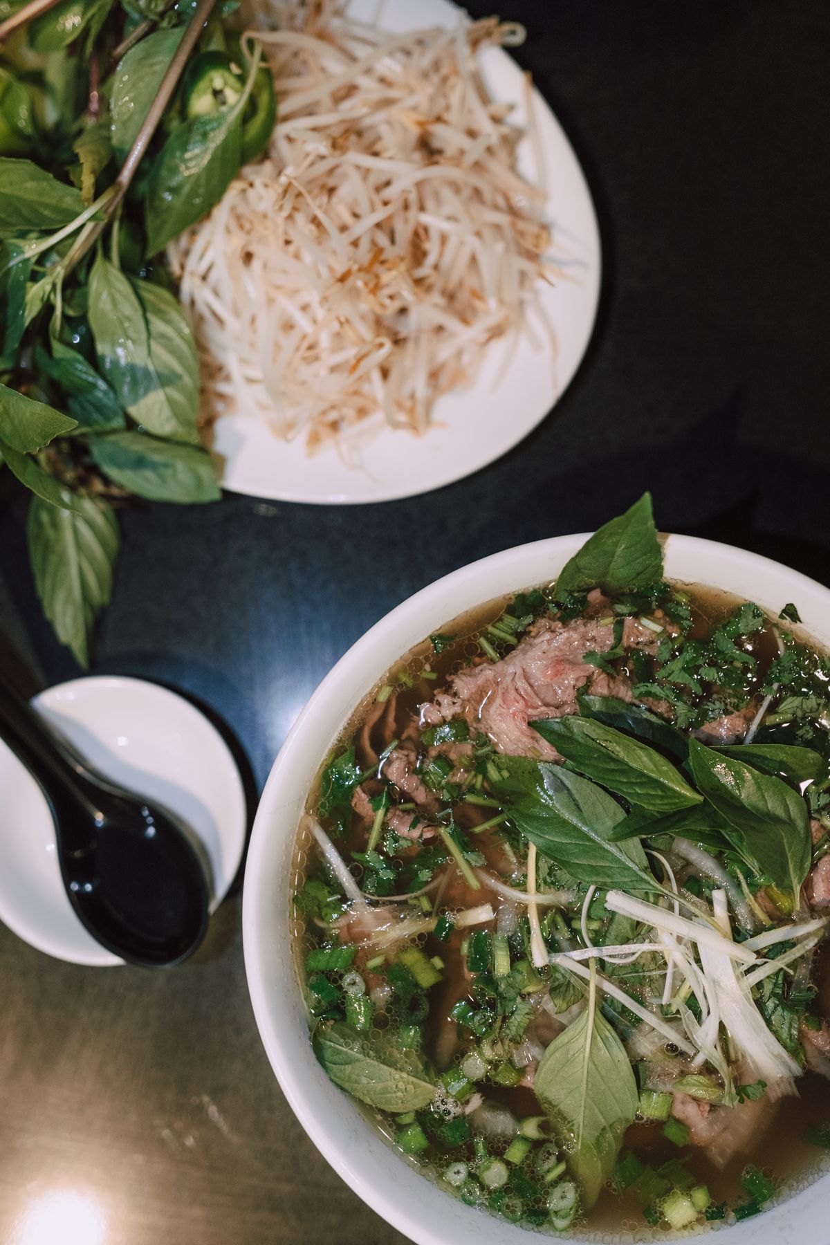 Pho bowl served with fresh basil and herbs on the side