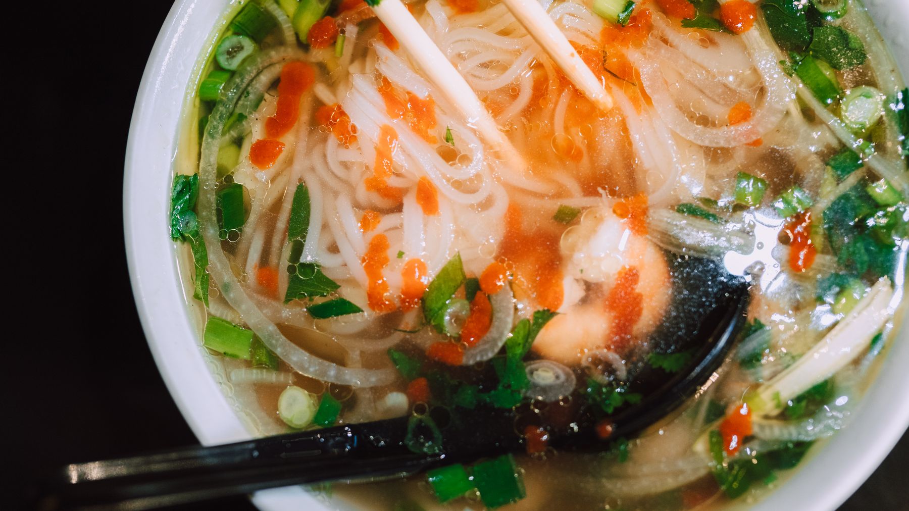 Delicious Asian noodle soup with vibrant garnishes captured in a close-up shot.