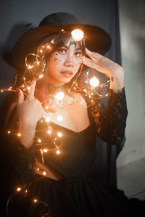Free Woman Wearing Her Black Costume with Fairy Lights  Stock Photo
