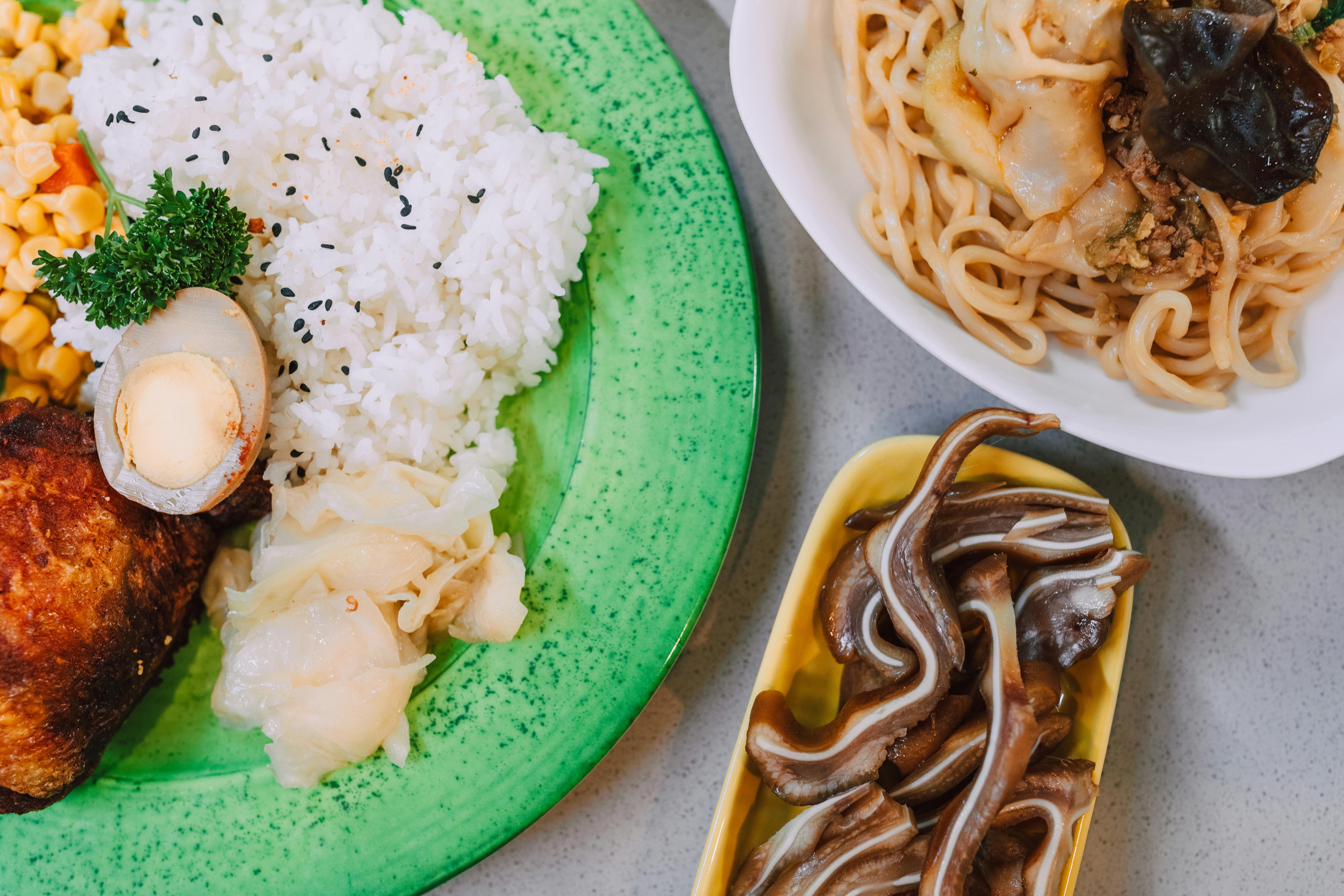 A vibrant Asian meal featuring rice, noodles, and unique dishes including marinated eggs.